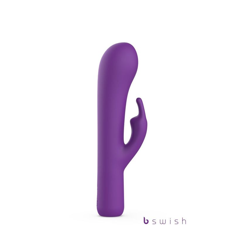 A purple silicone personal massager with a curved, finger-like stimulator arm, shown on a plain white background with a 'b swish' brand logo in the bottom right corner.